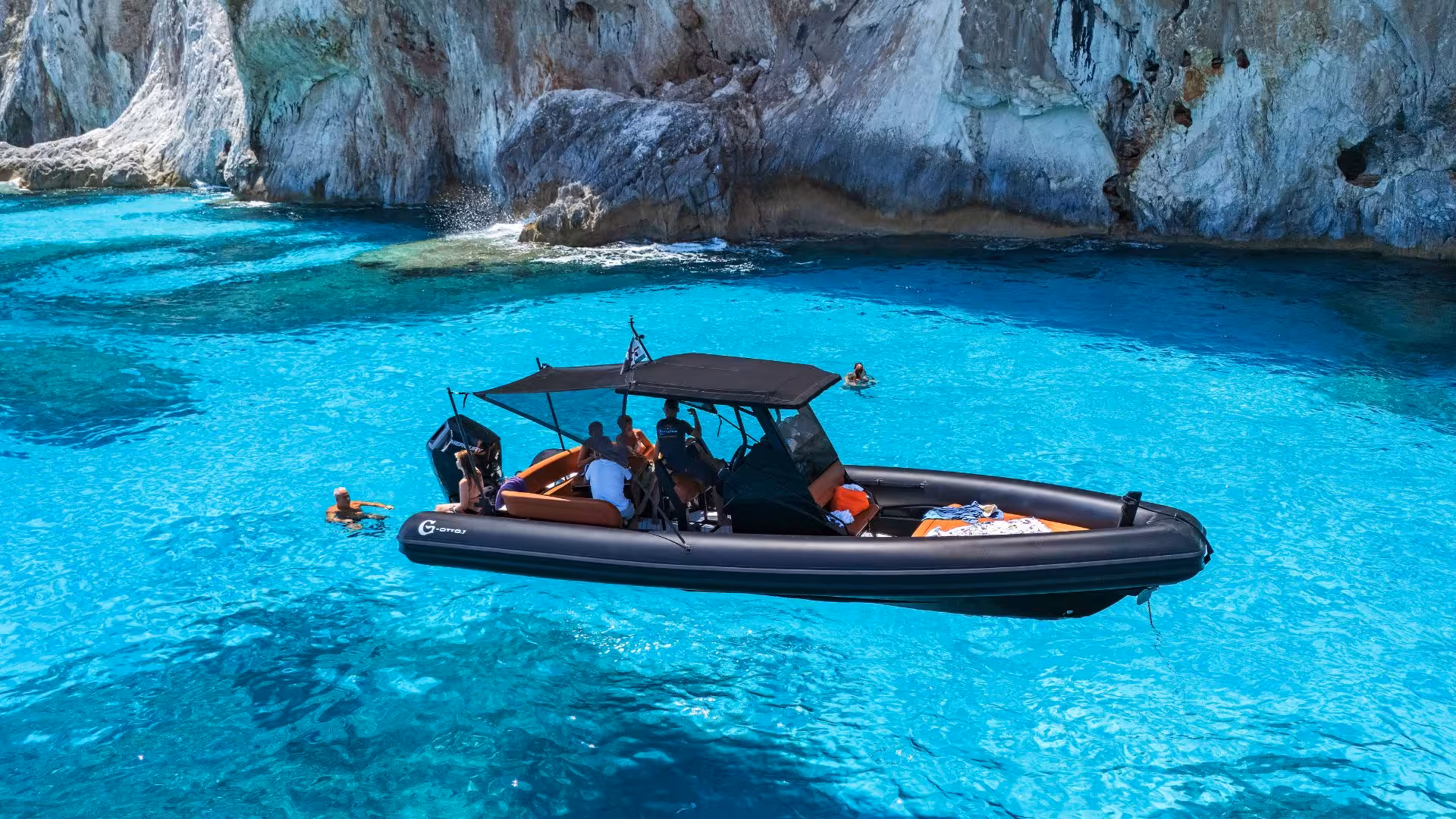 Dinghy anchored in vibrant turquoise water at Cala Luna, with passengers relaxing and swimming nearby.