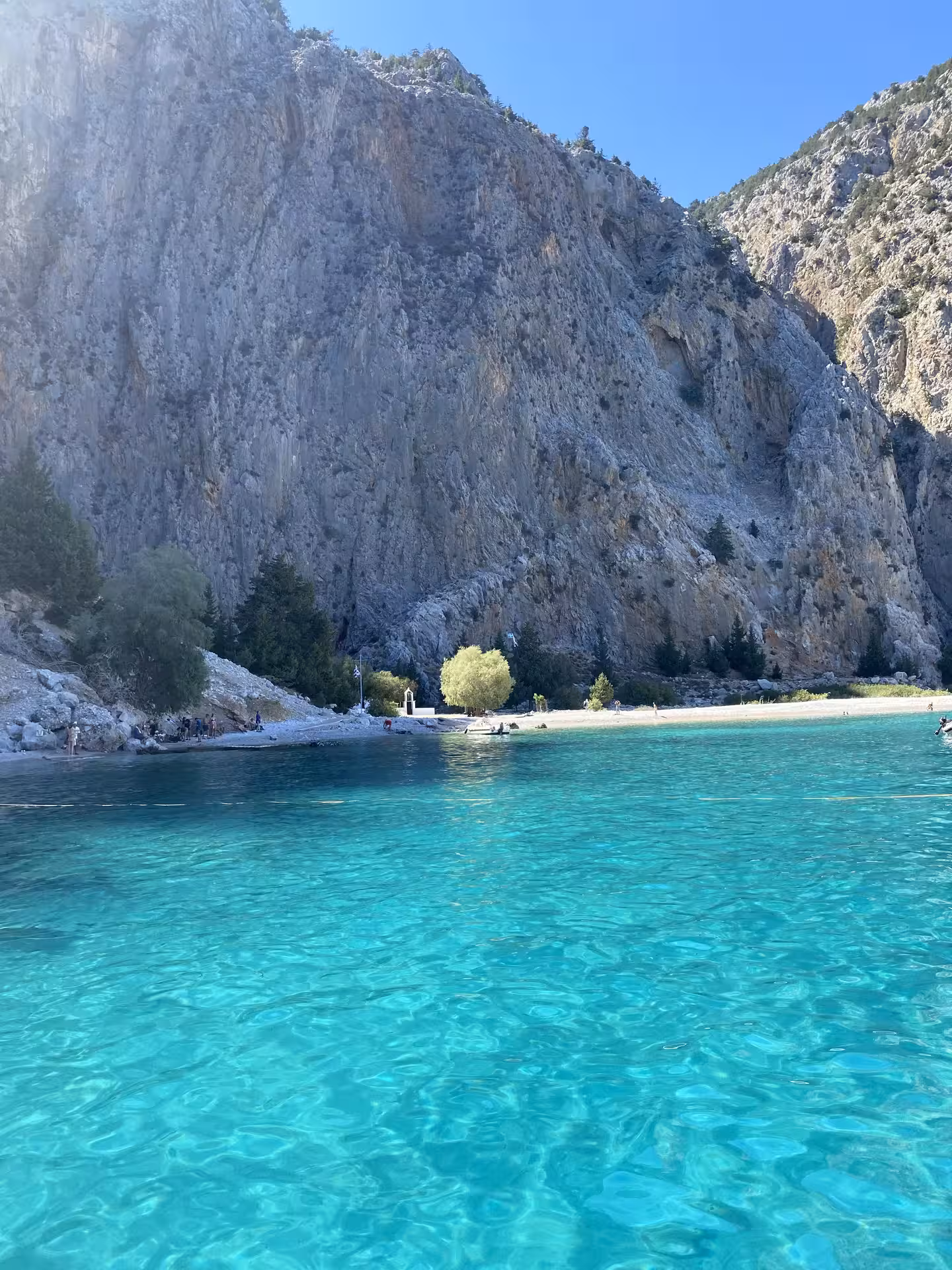 Turquoise bay beneath towering cliffs on the Discover Symi Axopar 25 CT cruise, perfect for swimming and photos