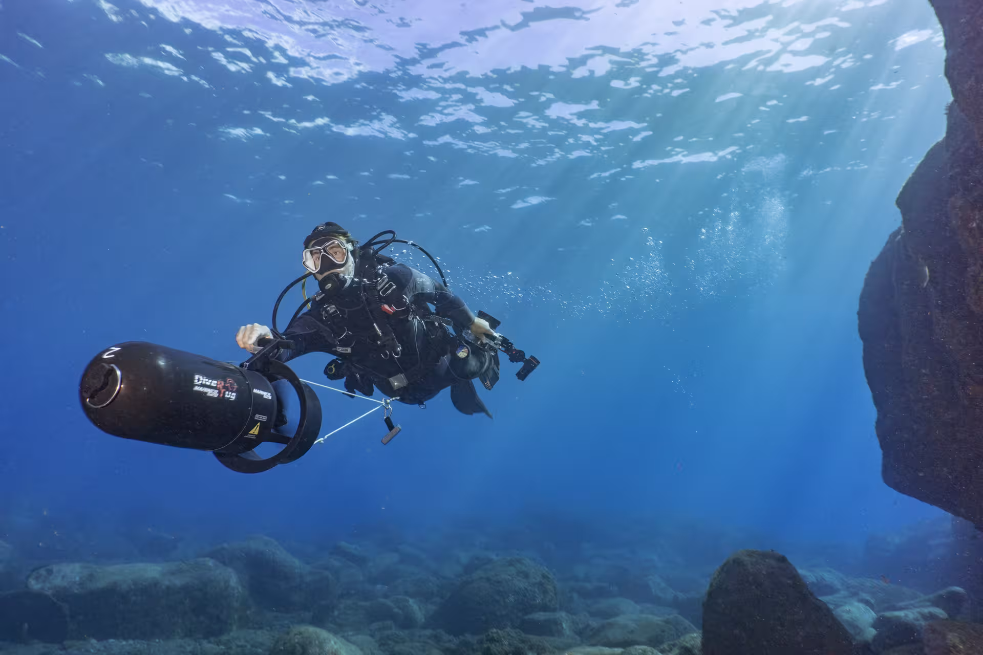 Diver exploring underwater with a DPV scooter, gliding through clear blue waters during a thrilling dive adventure.