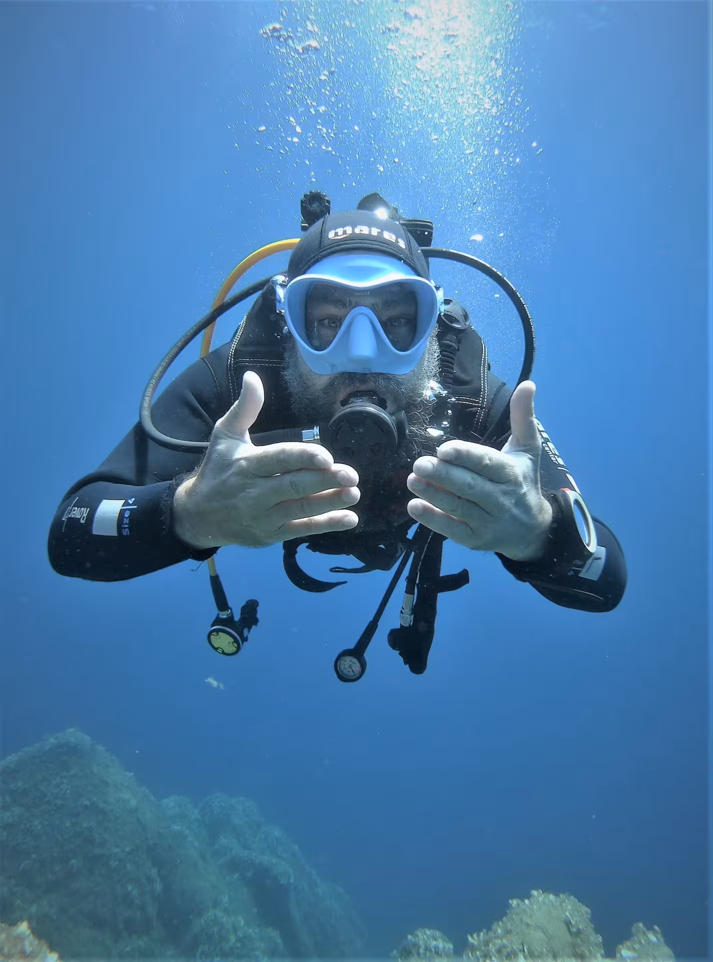 Diver giving hand signals underwater at Ruja Island during sea baptism tour from San Teodoro.