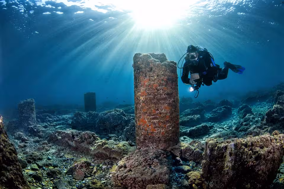 Diver swimming near a column of the "Portus Julius" site.