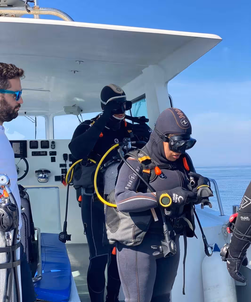 Divers checking masks and regulators on the dive boat for SCUBA REVIEW, guided pre-dive equipment setup