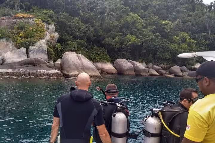 Group of divers with gear ready to explore the vibrant underwater world during the Diving Baptism tour by rocky shores.