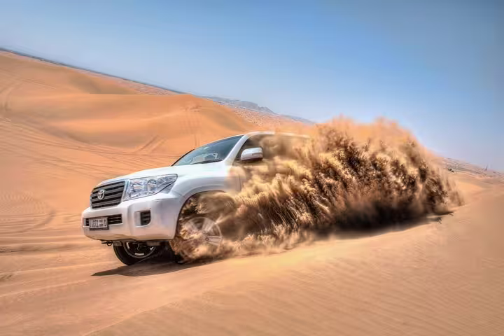 Off-road adventure in Qatar's desert with a 4x4 vehicle kicking up sand, part of an exhilarating Doha safari experience.