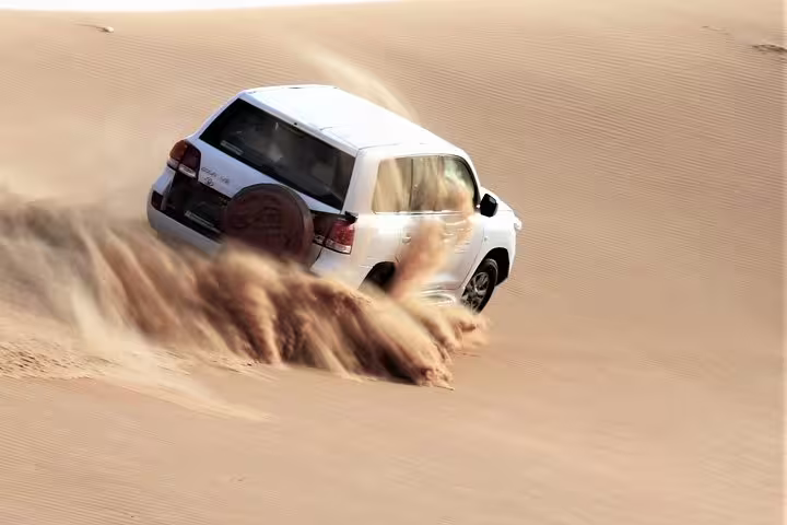 Off-road vehicle kicking up sand on an exhilarating desert safari experience in Doha.