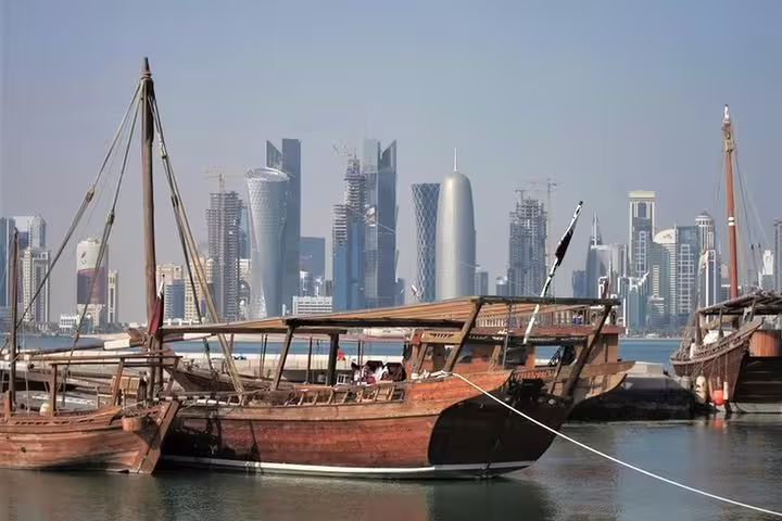 Traditional wooden dhow boats anchored with the Doha skyline in the background, blending heritage and modernity.