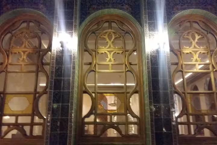 Intricate golden arched windows illuminated at night in Doha's vibrant cityscape.