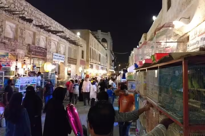 Bustling Souq Waqif in Doha at night, filled with people exploring traditional markets on the private city tour.