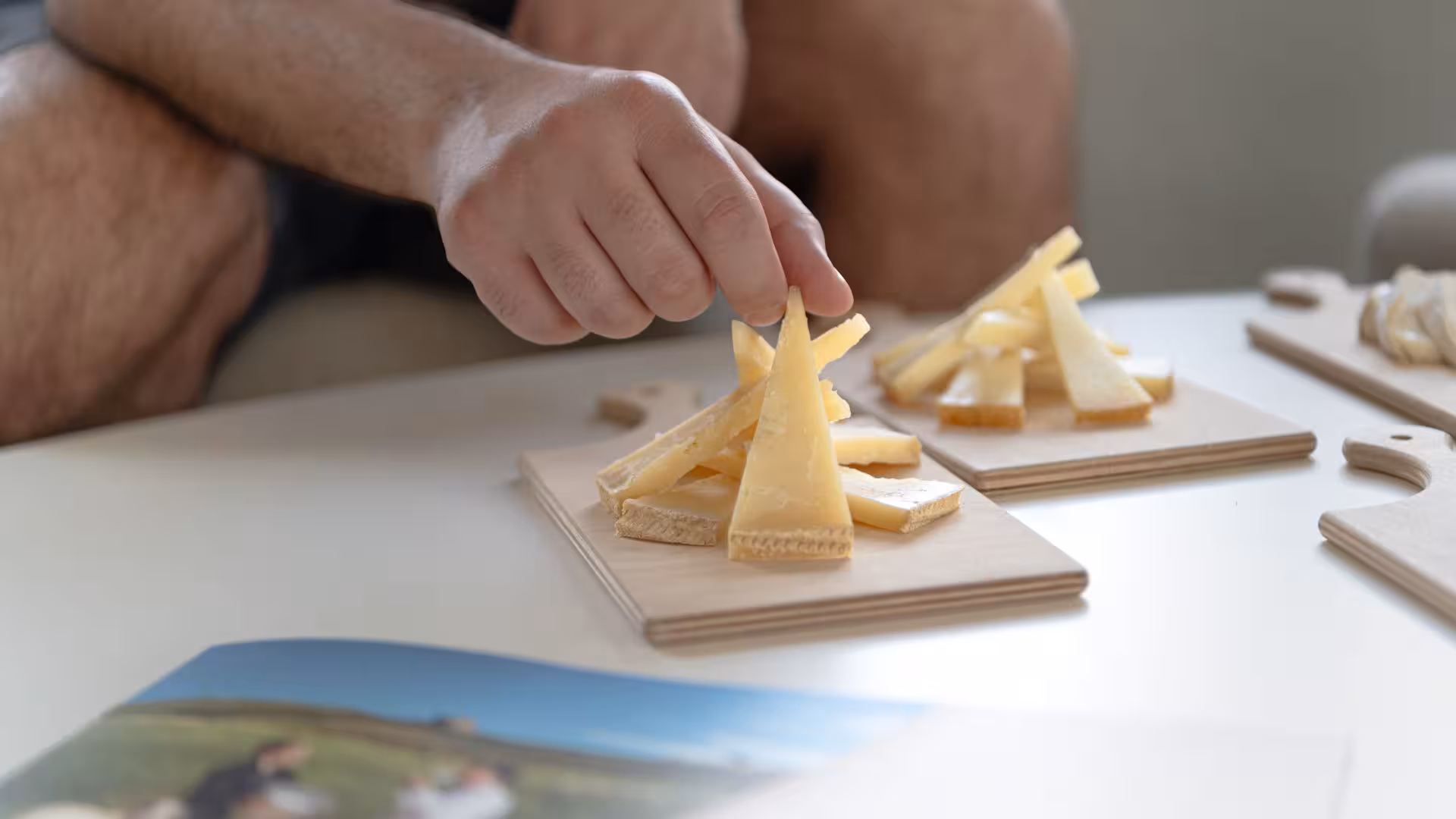 Close-up of a hand selecting cheese slices on a tasting board during Dolianova cheese factory tour.