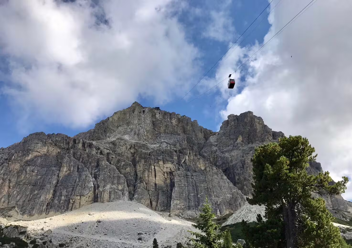 Cable car ascending rugged Dolomites peaks under blue skies, perfect for an adventurous day trip from Venice.