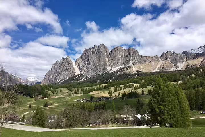 Breathtaking view of the Dolomites with lush green meadows and towering peaks on a sunny day.