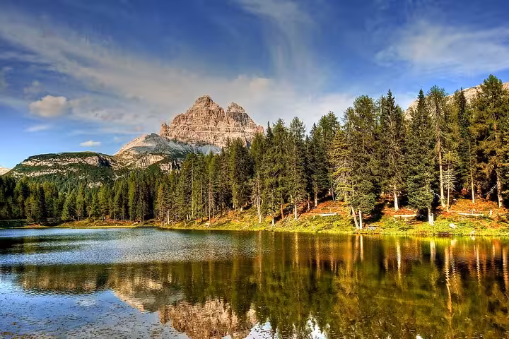 Scenic view of the Dolomites with a tranquil lake and lush forests, ideal for exploring from Venice.