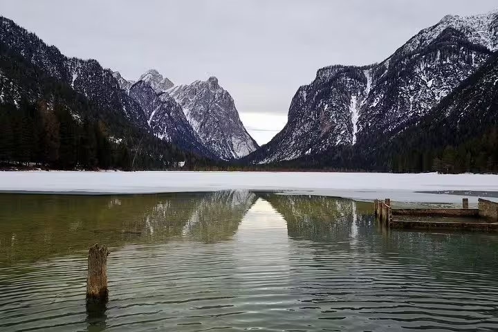 Peaceful Dolomites lake with snowy mountains, an inviting spot for a Venice to Dolomites day trip adventure.