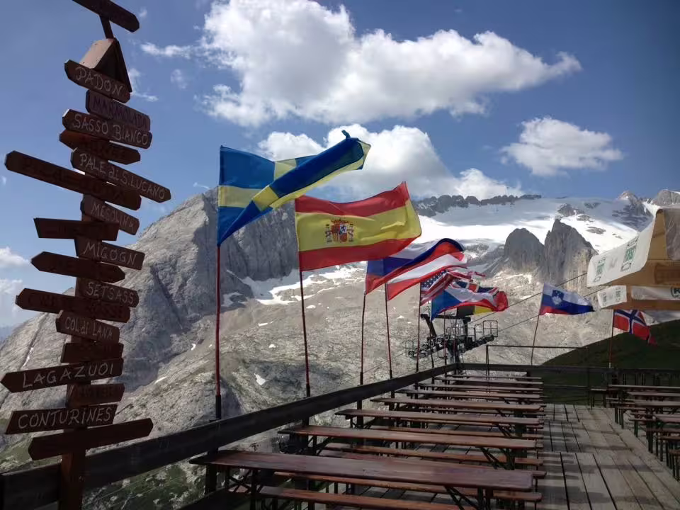 Flags flutter above a mountain terrace with stunning Dolomites backdrop on a Venice to Dolomites day tour.