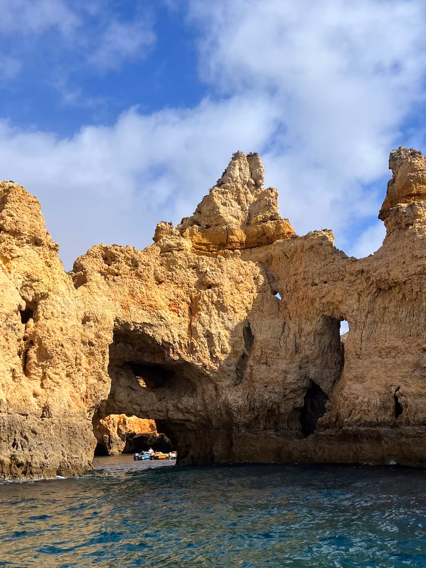 Small boat exploring dramatic rock formations and sea caves at Ponta da Piedade near Lagos on Algarve coast