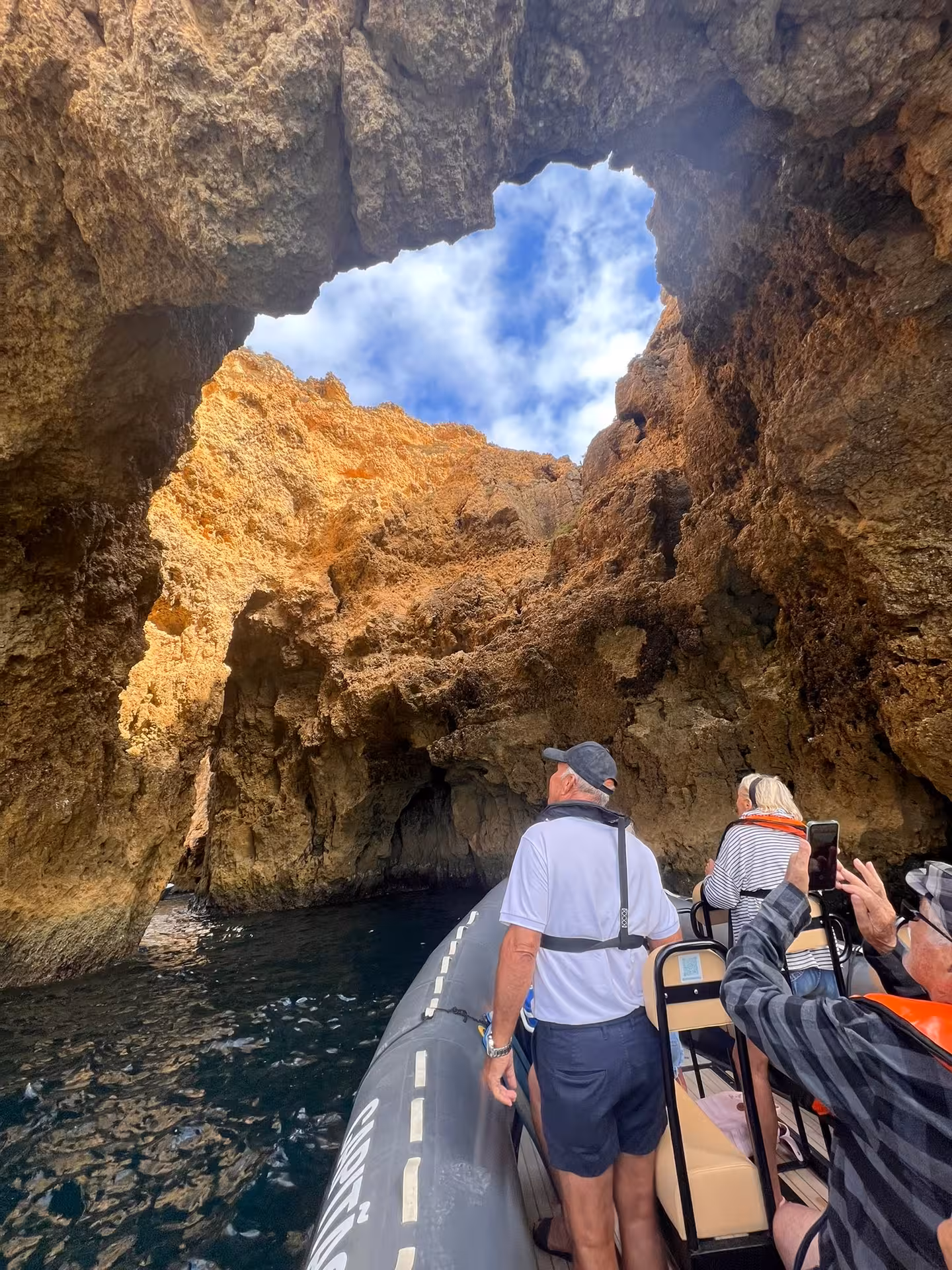 Guests on a small boat cruise beneath dramatic sea caves at Ponta da Piedade on a Lagos Algarve dolphin tour