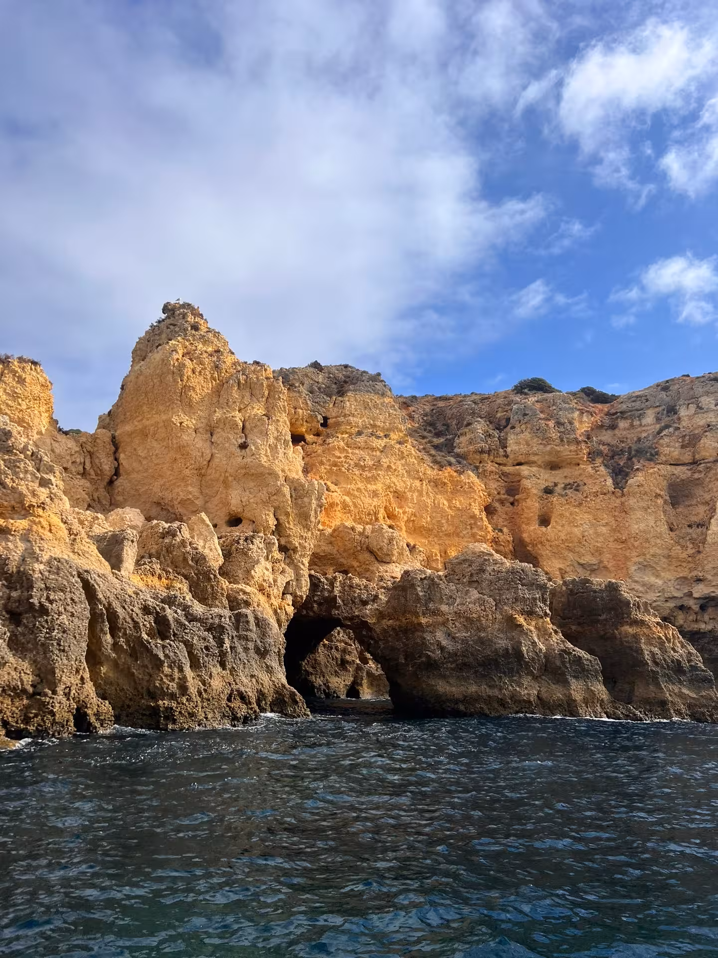 Golden limestone cliffs and sea cave arch at Ponta da Piedade rising above deep blue Atlantic waters near Lagos Algarve