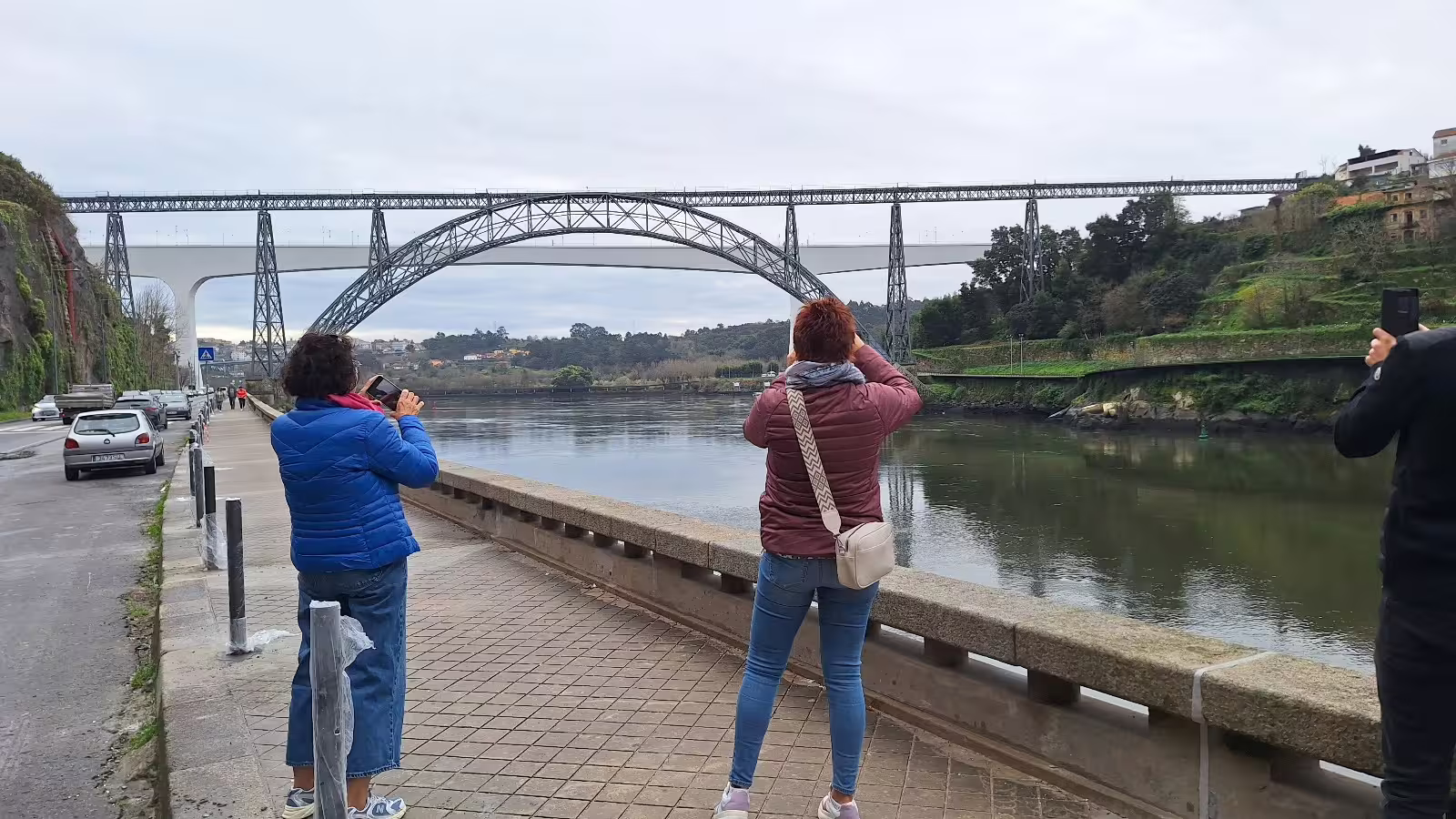 Tourists capture the scenic view of Dom Luís I Bridge in Porto during a private morning tour along the Douro River.