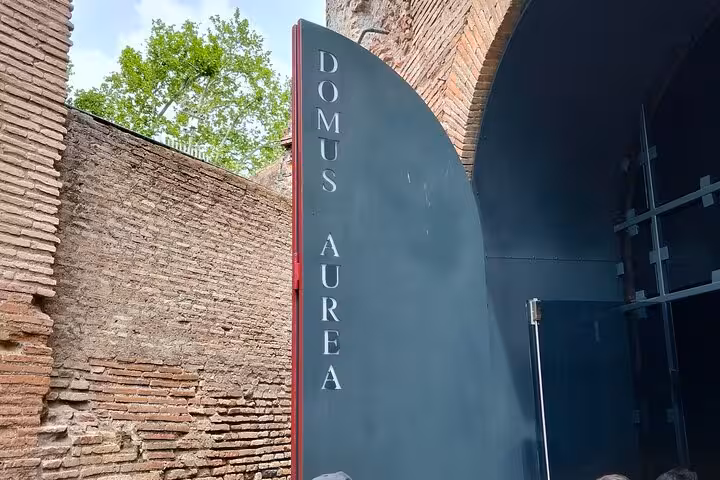Entrance to Domus Aurea in Rome, featuring a modern sign against ancient brickwork, inviting visitors to explore.