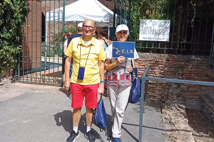 Tourists stand outside the entrance of Domus Aurea, holding a sign, ready for their immersive virtual reality tour.