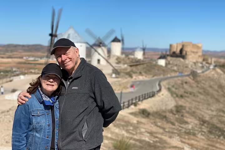 Couple enjoying the view of historic windmills and a castle on the Don Quixote Windmills tour in La Mancha.