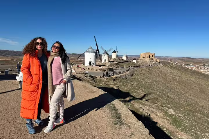 Two women pose in front of Don Quixote windmills on La Mancha tour, highlighting Spanish heritage and Toledo visit.