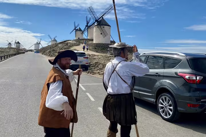 Guides in period costumes near La Mancha windmills, offering an immersive Don Quixote tour experience.
