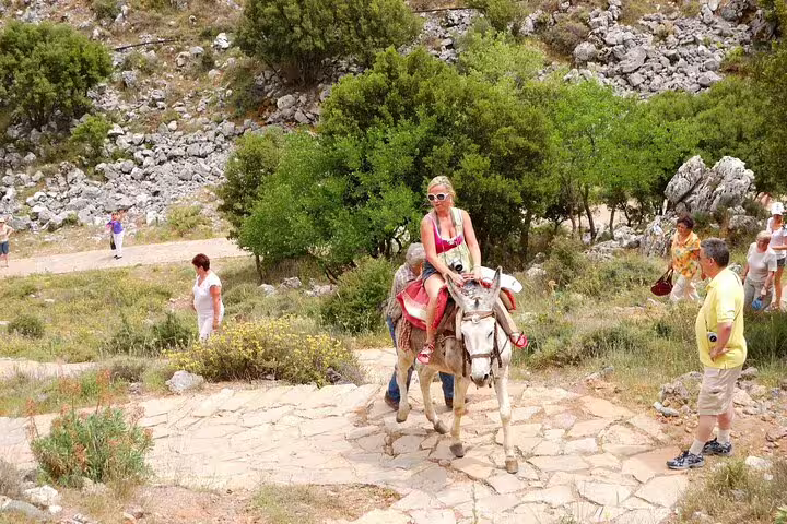 Tourists enjoy a donkey ride along the rocky paths near Zeus Cave on a private tour from Chania.