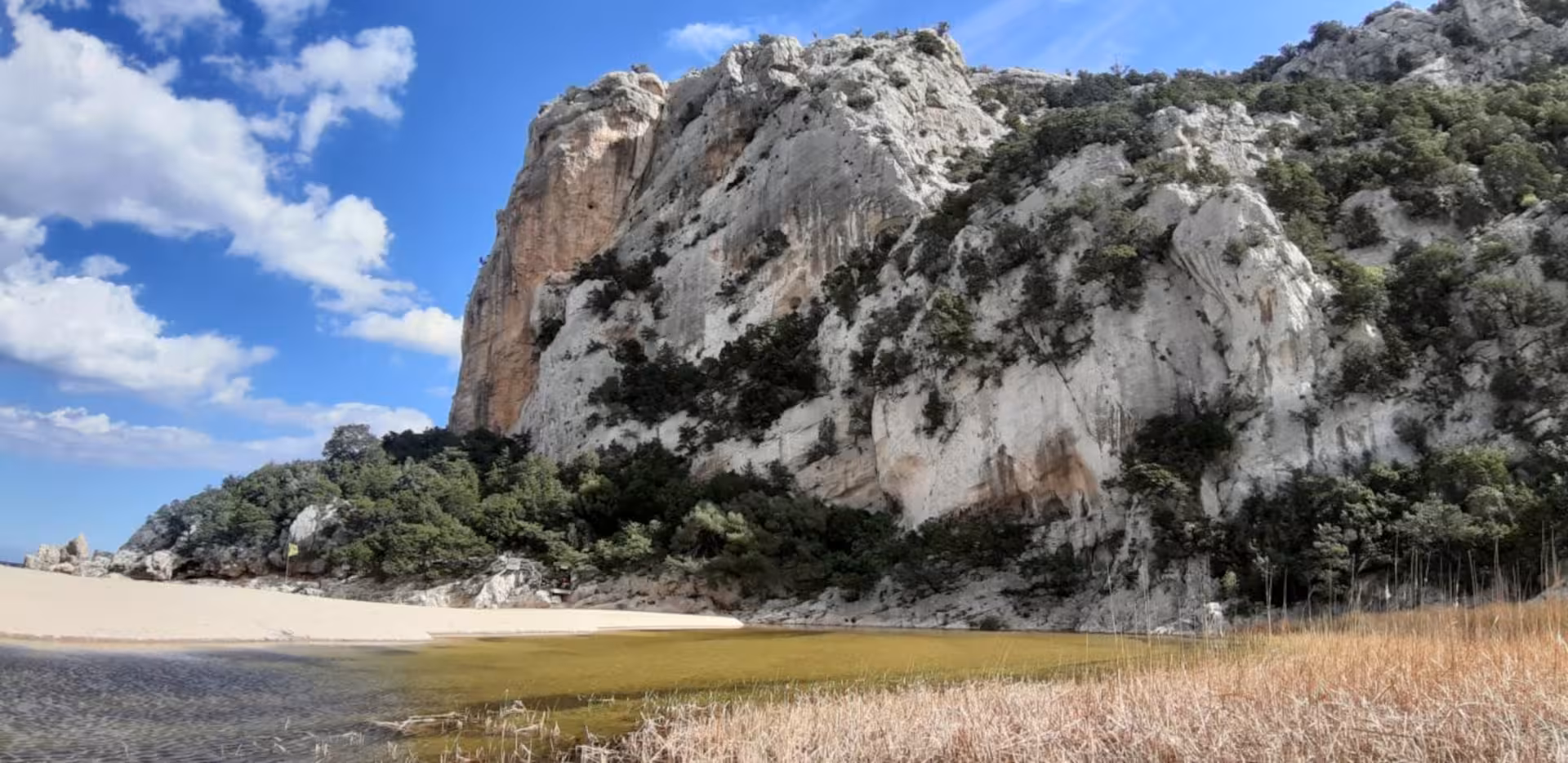 Majestic limestone cliffs and sandy beach at Cala Luna, a highlight on the Dorgali trekking tour.