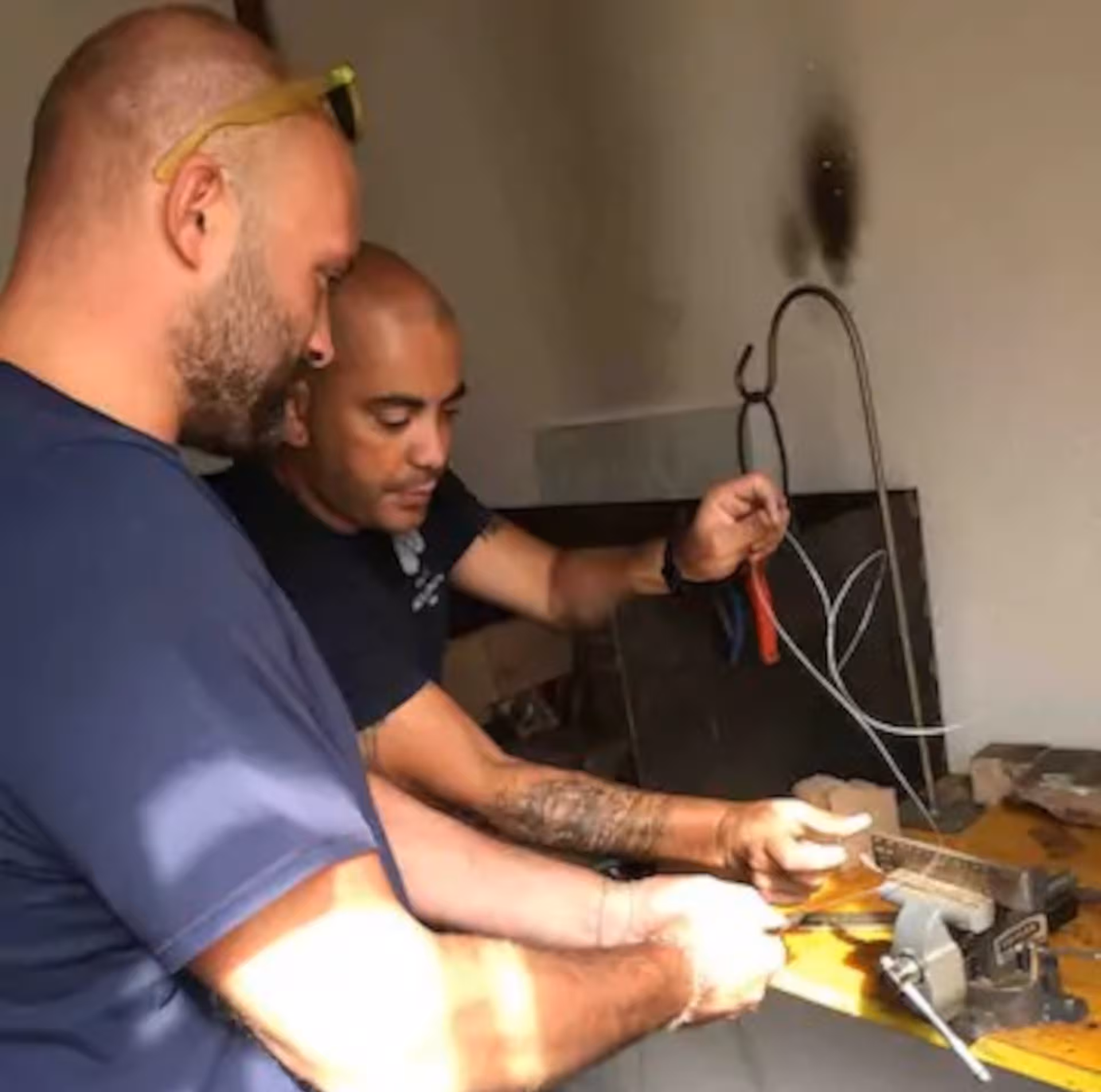 Two artisans collaborating on filigree techniques in a Dorgali goldsmith's lab, showcasing Sardinian craftsmanship.