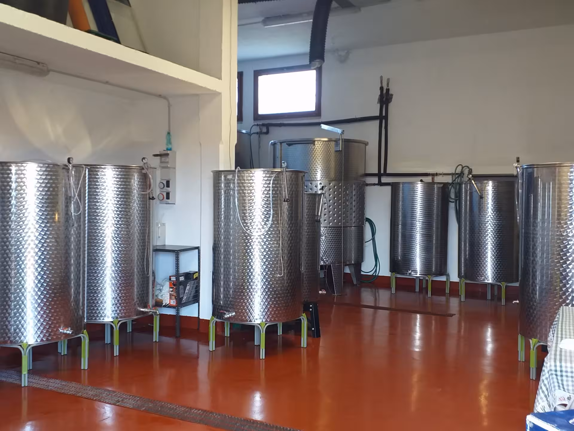 Stainless steel fermentation tanks in a Dorgali winery, showcasing the winemaking process for an authentic tasting tour.