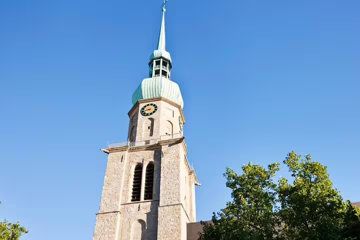 Dortmund church tower with clock and spire against blue sky, landmark on a self-guided scavenger hunt tour