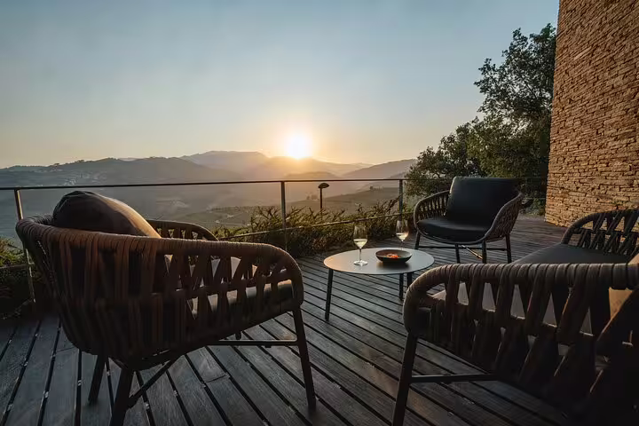 Sunset view from a luxurious patio with seating on a Douro private cruise, offering serene river and mountain scenery.
