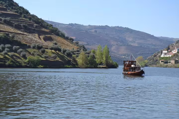 Traditional boat cruising on the Douro River with terraced vineyards in the background.
