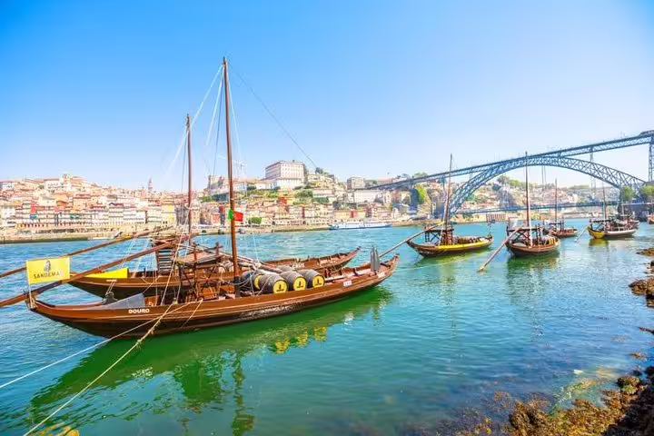Traditional boats on Douro River with Porto's iconic bridge in the background, perfect for Régua return boat tour.