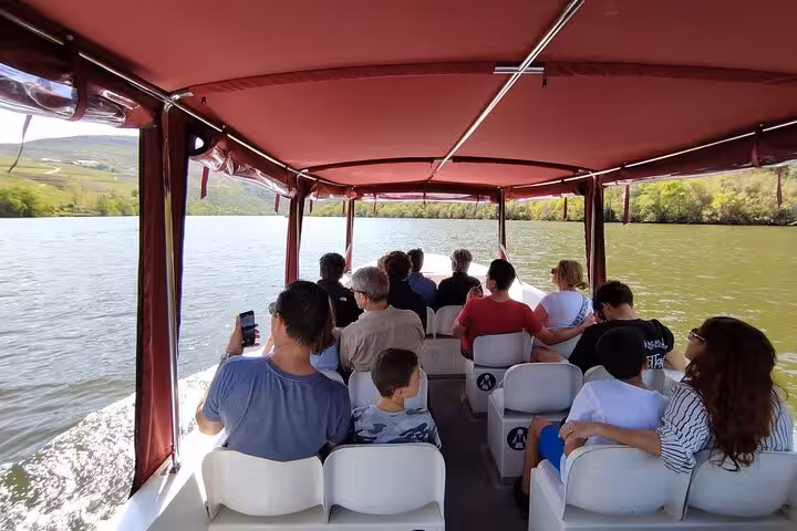 Guests enjoying a Douro River cruise boat ride, premium tour with panoramic vineyard views in Portugal