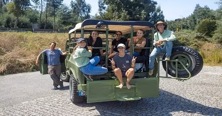 Group riding vintage 4x4 jeep on Douro River tour, exploring scenic beaches, mills and hidden gems