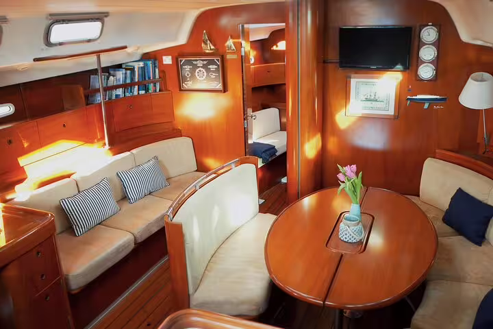 Cozy and elegant interior of a sailboat cabin with plush seating, wooden decor, and floral centerpiece for Douro Sunset Sailboat Experience in Porto.