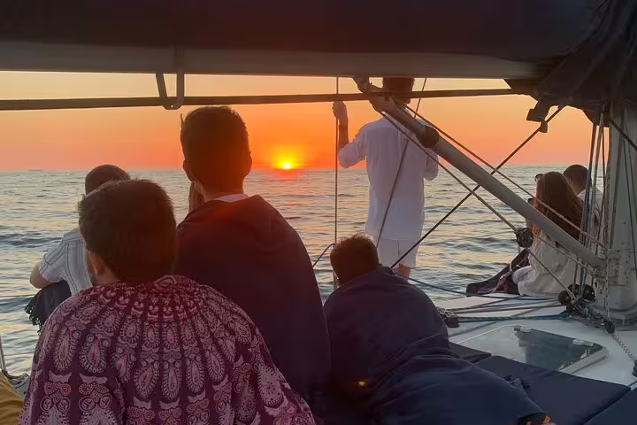 People enjoying a serene Douro River sunset sailboat experience in Porto, capturing the vibrant hues of the evening sky.