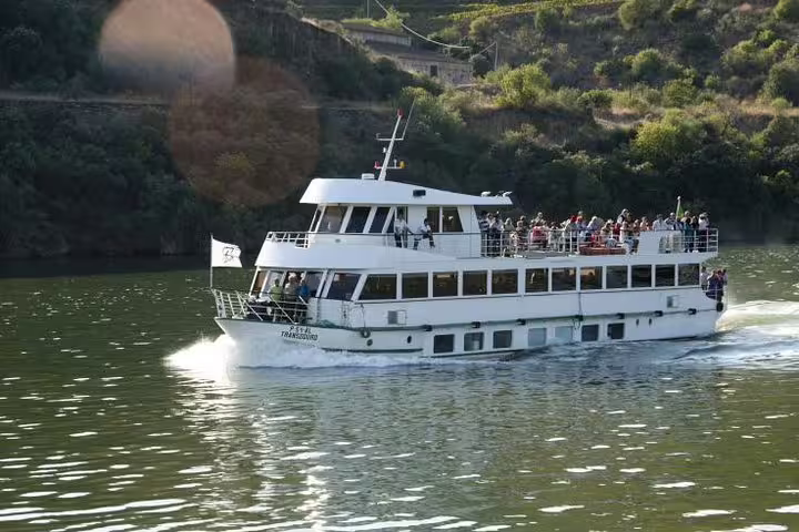 Scenic boat cruising through the Douro Valley, offering breakfast and lunch with lush hillside views.