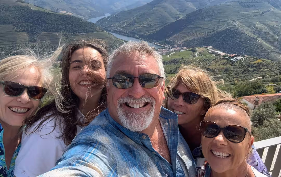 Group selfie at a Douro Valley viewpoint with river and terraced vineyards, highlight of a panoramic tour
