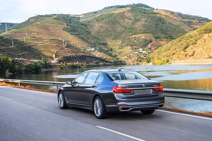 Private Douro Valley tour car driving riverside past terraced vineyards en route to wineries and tastings
