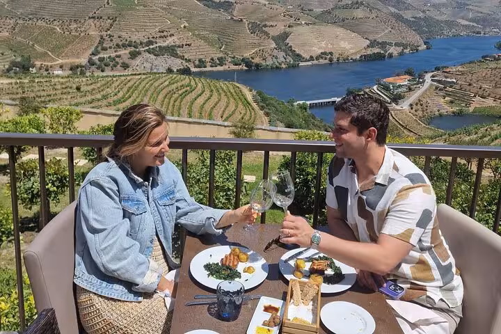 Couple enjoying lunch and wine tasting on Douro Valley terrace with river views on private guided winery tour