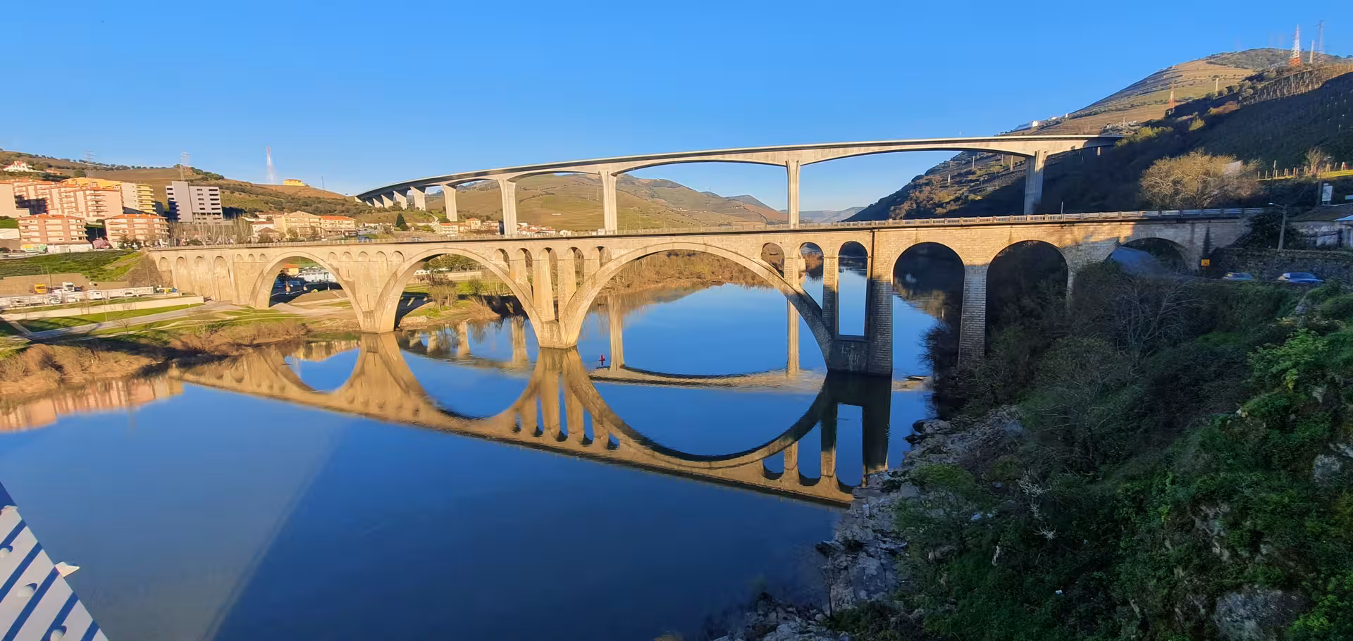 Arched bridge reflected on calm river in northern Portugal, route on Douro Valley train tour and Vinho Verde wine