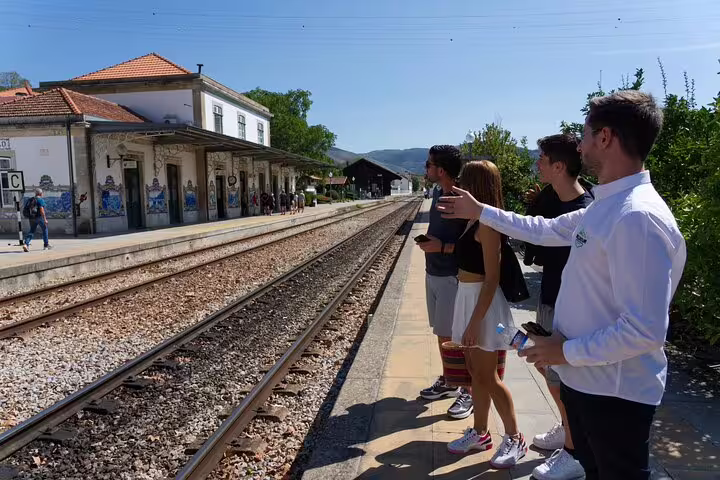 Group of tourists waiting at picturesque Douro Valley train station for a scenic ride experience.