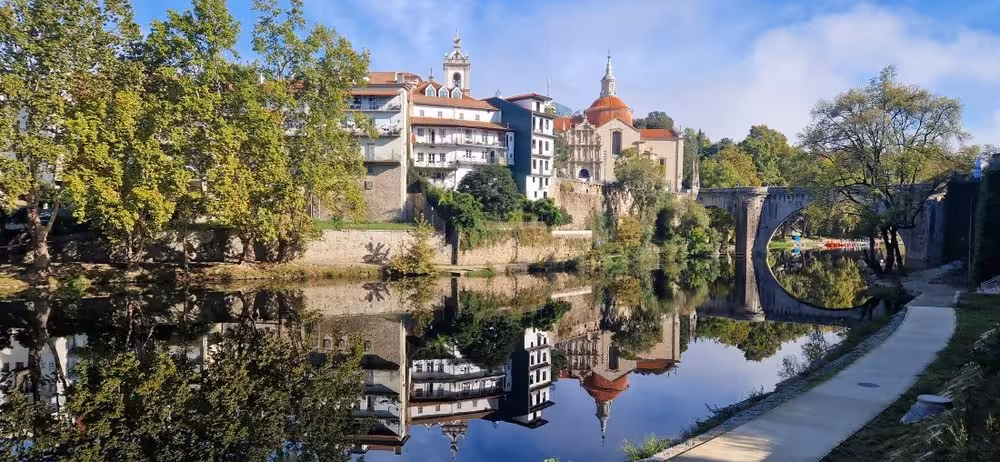 Riverside town and arched bridge reflected on calm water, scenic stop on private Douro Valley train tour
