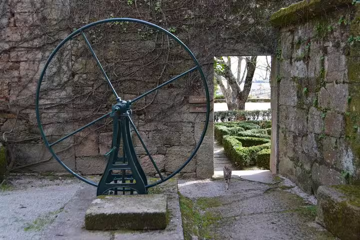Historic vineyard gate with large wheel in Douro Valley, showcasing rustic charm and scenic views from Porto tour.