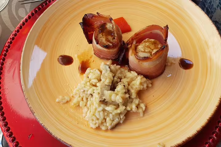 Gourmet meal featuring bacon-wrapped delicacies and creamy risotto, served during a Douro Valley vineyard lunch.