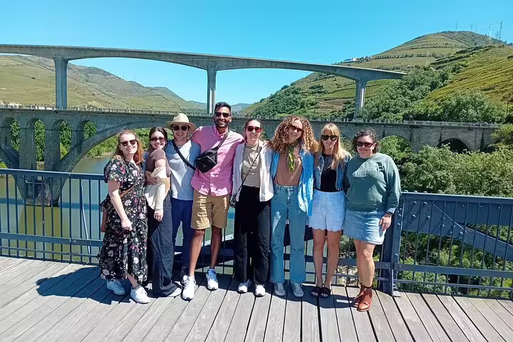 Group enjoying scenic views of Douro Valley vineyards and bridges during a vineyard visit tour.