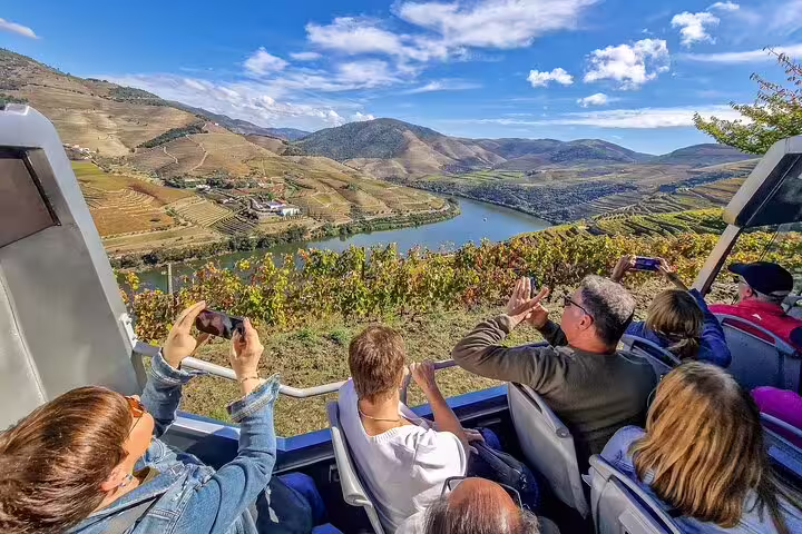 Tourists enjoy breathtaking views of Douro Valley vineyards and river on a scenic private tour from Lisbon, Portugal.